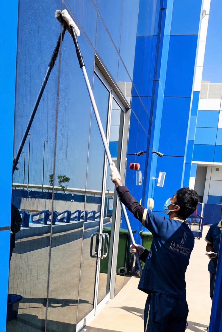 La Marquise technician cleaning a glass facade with an extension pole